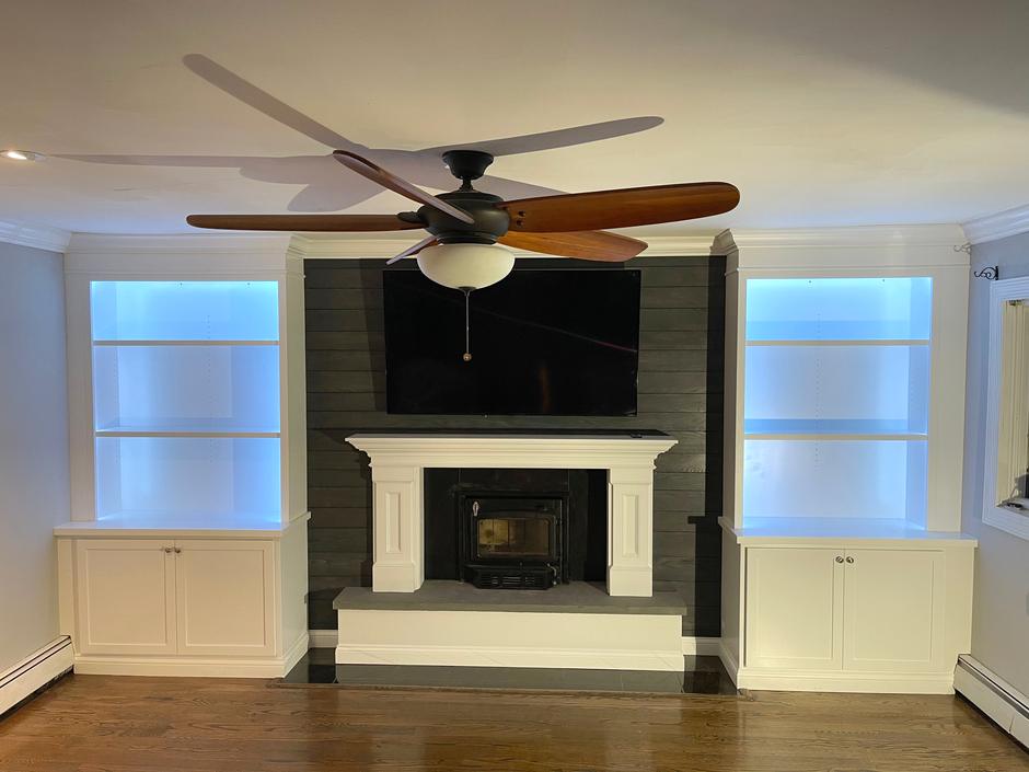 Finished: white built-ins with lit shelves on both sides of a dark shiplap chimney wall