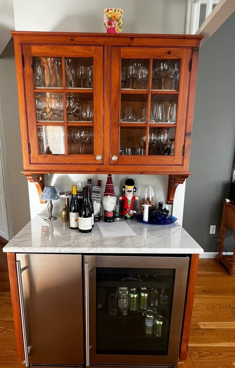 Before: a bar hutch in an orange-brown wood finish, with glass doors above and a wine fridge under the counter