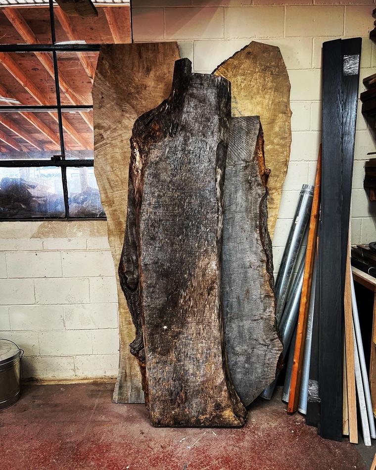 Tall live-edge slabs standing against a concrete-block wall in a workshop