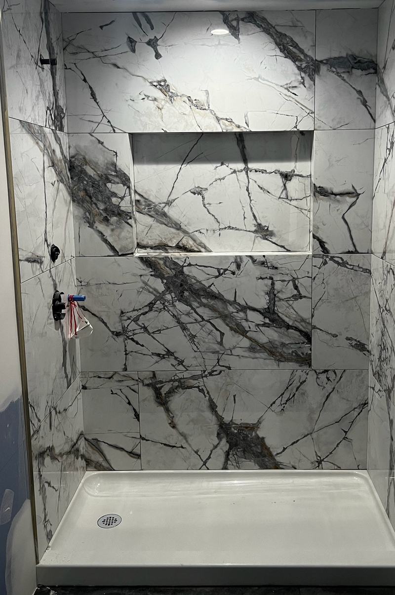 After: the same shower tiled to the ceiling, with a long niche and a white base