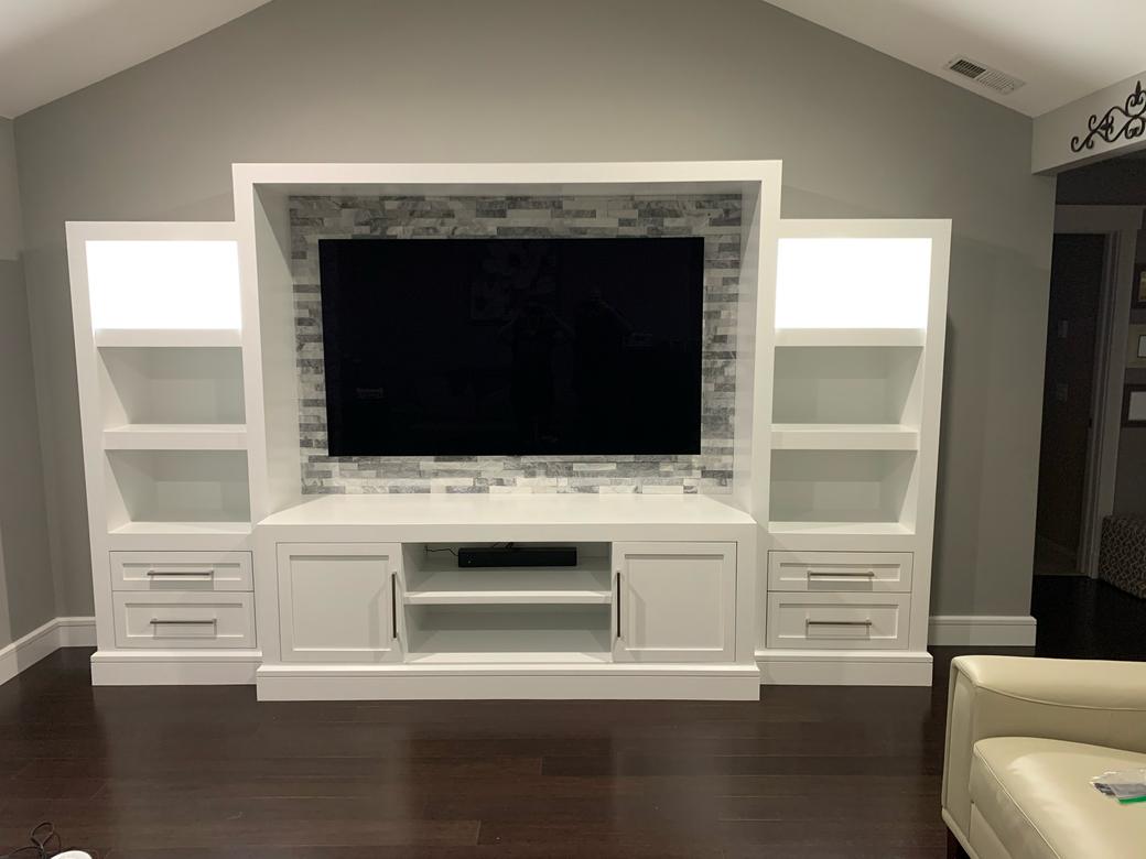 Finished white entertainment wall with the TV mounted and the upper shelves lit