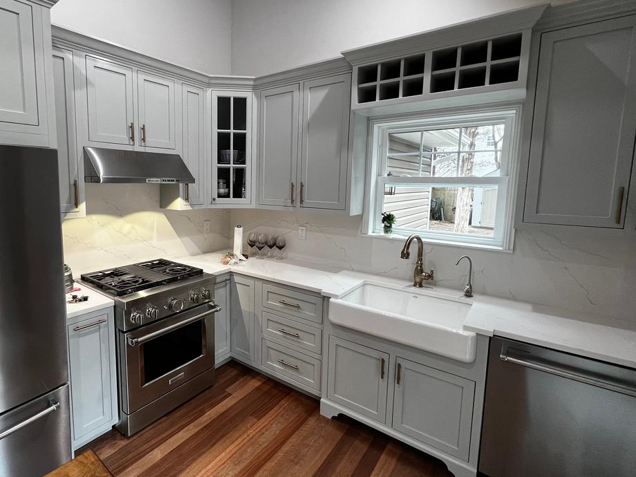 Gray kitchen seen from the island: range and hood, a glass-front corner cabinet and a window with a wine rack above