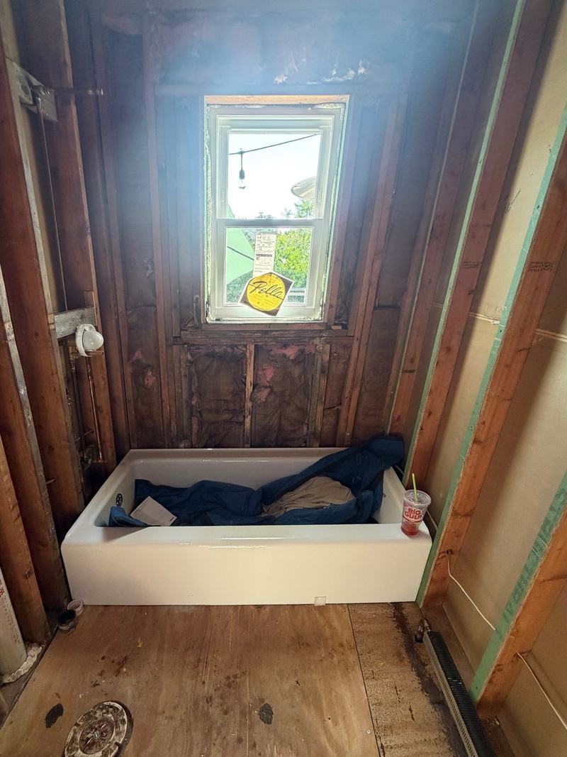 Before: a bathroom taken down to the studs, a tub set under the window
