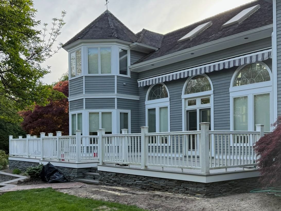 After: the same deck with white railings, posts and trim on the stacked stone foundation