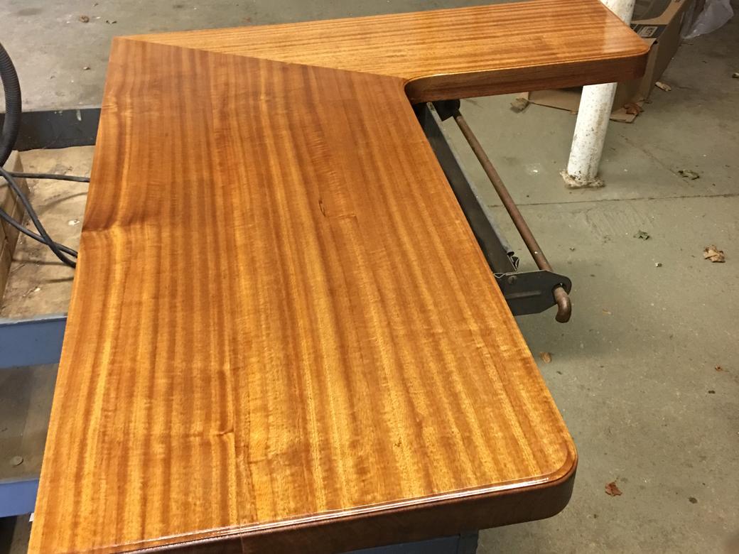 The finished L-shaped desktop, its grain showing, on a cart in the shop